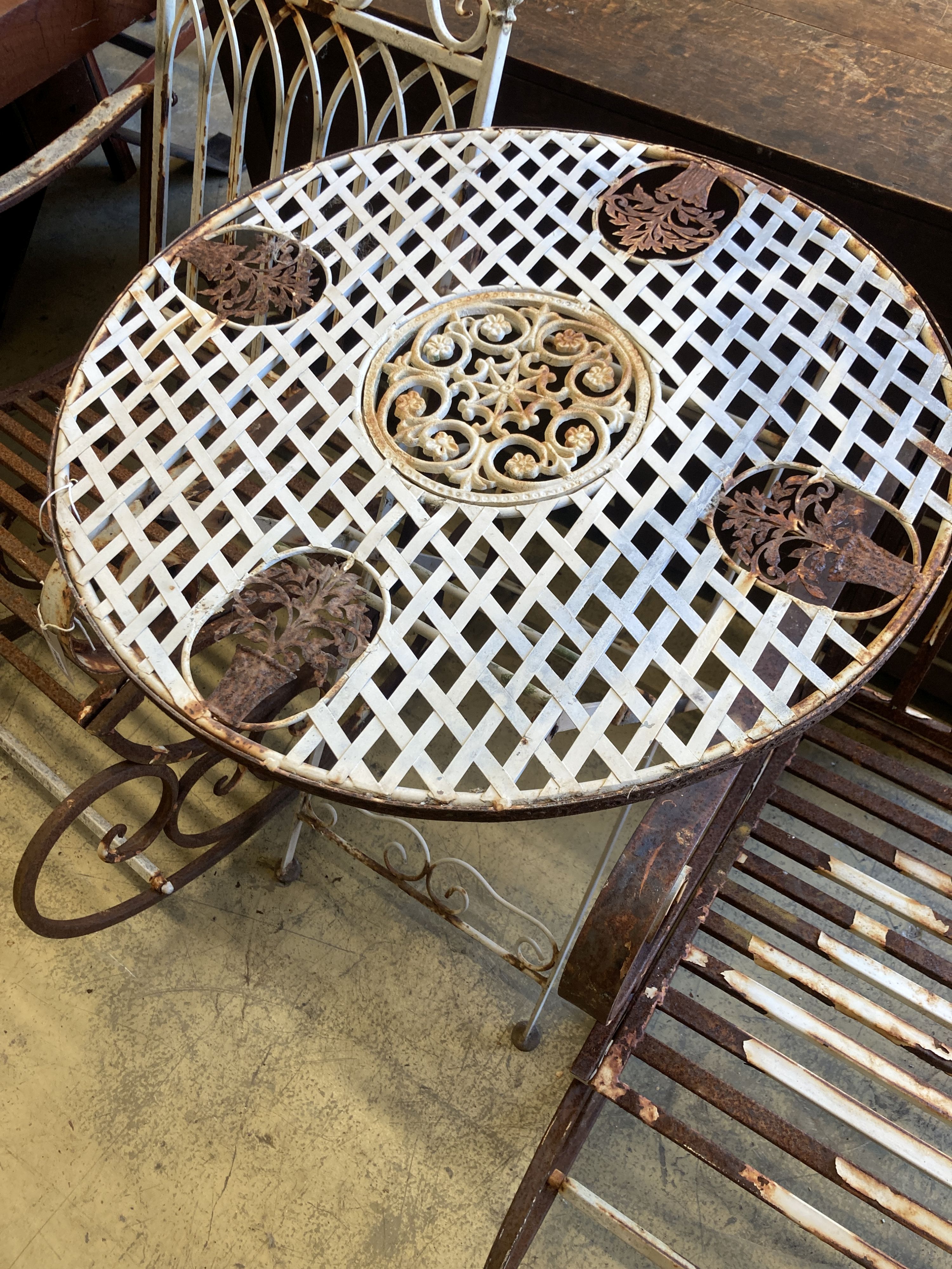 A pair of painted wrought iron garden rocking chairs together with a circular wrought iron folding garden table, diameter 71cm, height 76cm